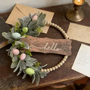 Close-up detail of Easter wreath with hello wooden sign, green leaves, and speckled eggs