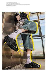 Detailansicht der schwarzen Mech-Design-Slipper am männlichen Modell im Streetwear-Stil