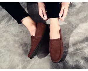 Vue détaillée de mocassins en daim marron pour hommes portés sur un beau sol gris