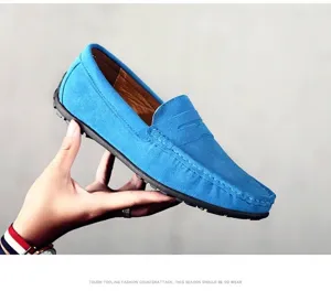Main tenant un élégant mocassin en daim bleu ciel pour homme sur fond gris neutre