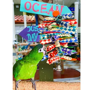 Close-up of a colorful woven paper bird toy with a green parrot interacting on a perch