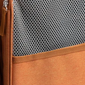 Primer plano detallado de la malla gris transpirable en una mochila naranja para gatos