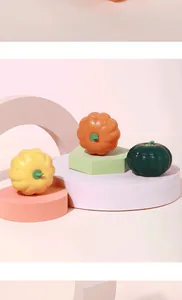 Drei bunte Katzenminze-Spielzeuge in Kürbisform auf pastellfarbenen geometrischen Ständern