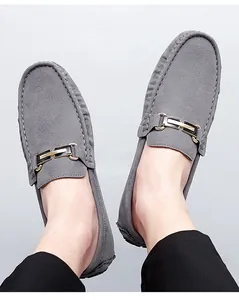 Close-up view of elegant grey suede loafers with metal buckle detail worn by a person