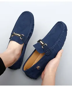 Detail view of blue suede loafer shoes featuring decorative metal buckle hardware.