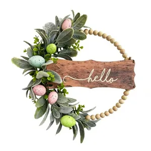 Close-up of Easter wreath with lamb's ear leaves, colorful eggs, and wooden 'hello' sign.