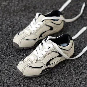 Retro beige Bundeswehr-Sportschuhe mit schwarzen Akzenten auf Asphalt-Hintergrund