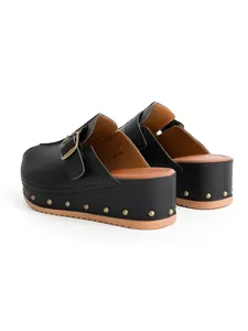 Vue arrière de sabots à plateforme noirs avec clous métalliques et boucle décorative.