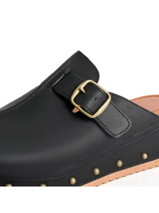 Détail en gros plan d'une mule en similicuir noir avec boucle et rivets décoratifs
