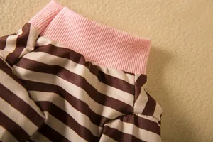Macro view showing the pink ribbed elastic cuff and brown striped fabric of a dog shirt.