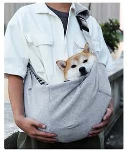 Breathable gray pet sling carrier with adjustable strap shown with a dog for outdoor travel