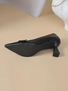Gros plan d'escarpins noirs à motif crocodile avec bout pointu et talon bloc élégant