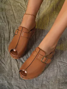 Gros plan de sabots plateforme marrons pour femmes avec boucle et détails de rivets.