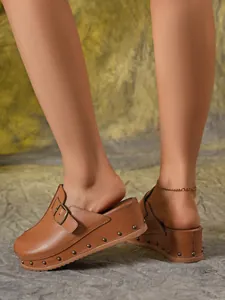 Gros plan de mules à plateforme marron avec rivets décoratifs et bride à boucle