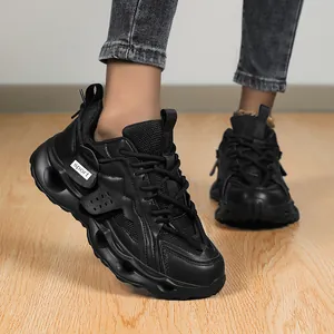 Close-up detail of black chunky platform sneakers featuring a stylish sport tag on the side