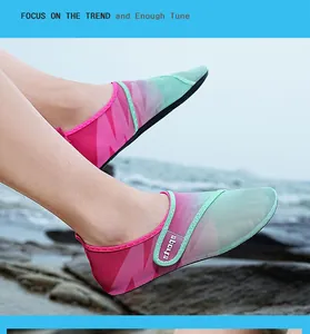 Dettaglio di scarpe da scoglio traspiranti rosa e verdi con velcro sulla spiaggia