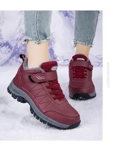 Detailaufnahme von weinroten wasserdichten Winterschuhen mit warmem Fellfutter im Schnee