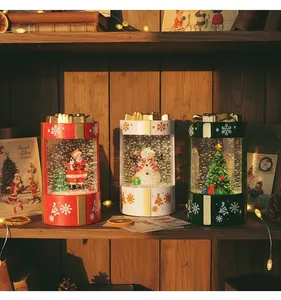Set of three glowing Christmas snow globe lanterns in gift box shapes on a shelf