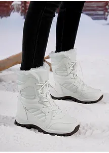 Detail of white women's winter snow boots with fleece lining on snow background.