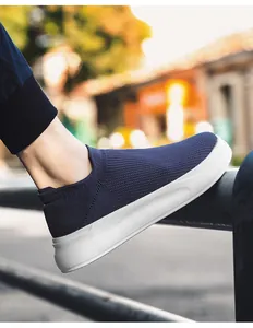 Detail of navy blue fly-knit breathable slip-on men's sneaker with white thick sole.
