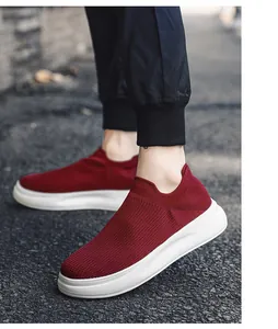 Close-up of red breathable flyknit slip-on sneakers for men on outdoor asphalt street