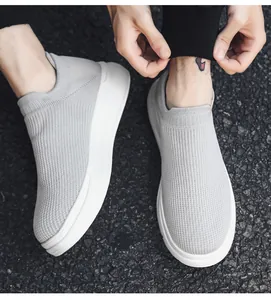 Detail view of breathable grey knit slip-on sneakers for men worn on outdoor asphalt