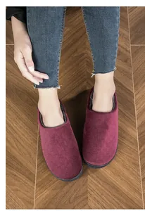 Macro detail of comfortable burgundy indoor slippers with warm plush lining on floor