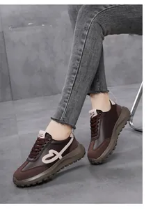 Close-up of stylish retro brown sneakers featuring heart embroidery and platform soles on model