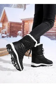 Detailed side view of black women's snow boots with white fur lining on snowy ground