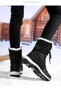 Detail view of black mid-calf snow boots with faux fur lining and EVA sole on snow