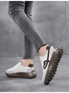 Detail shot of white sneakers with heart embroidery and brown thick platform sole.