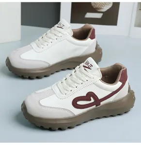 Detailed view of retro white sneakers featuring burgundy heart embroidery and thick soles