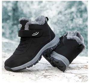 Detailed side view of black high-top snow boots with grey faux fur lining in snow.