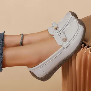Close-up of light grey soft-sole loafers on feet with butterfly bow detail