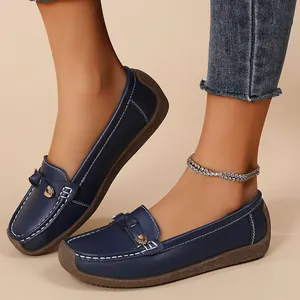 Close-up detail shot of dark blue leather loafers featuring white stitching and flexible sole