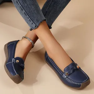 Close-up view of dark blue leather loafers featuring white stitching and gold metal accents