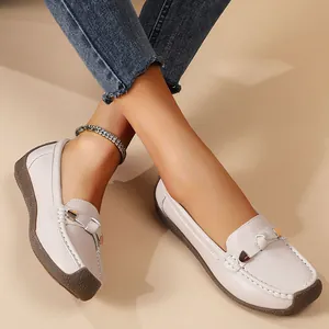 Macro view of women's beige leather loafers with metal buckle on model's feet