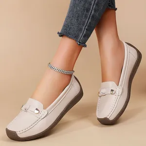Close-up view of beige soft leather loafers with metal buckle worn on model's feet