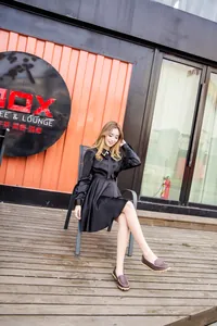 Asian model wearing stylish brown leather loafers and a black dress in an outdoor setting