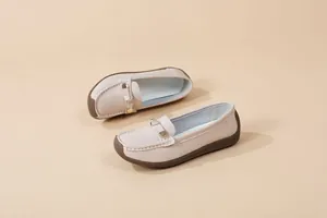Close-up of elegant beige soft-sole slip-on loafers with metallic buckle decoration