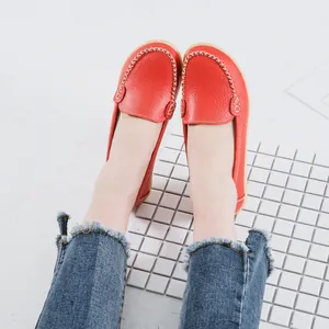 Detailed view of casual red leather loafers with hand-stitched finish worn with jeans.