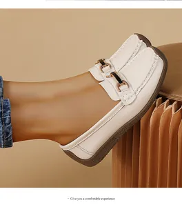 Detailed side view of comfortable white leather loafers with elegant metallic buckle for women