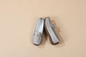 Detailed view of women's grey slip-on loafers featuring pebble grain leather and a metal buckle