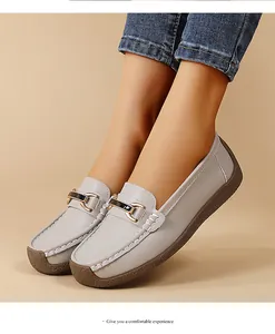 Close-up view of elegant grey leather loafers with gold buckle detail on feet for women