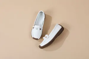 High-angle detail view of white casual loafers featuring soft soles and a slip-on design for women