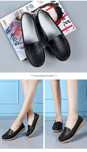 Detail of black leather loafers with hollow-out design and wedge heel worn by model.