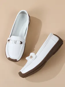 Detailed view of white soft-sole women's loafers with metallic buckle and brown rubber sole