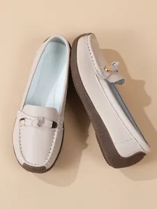 Detail view of beige soft-sole loafers with metal buckle and elegant white stitching
