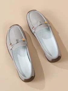 Detail view of grey soft leather loafers with elegant gold buckle and stitching