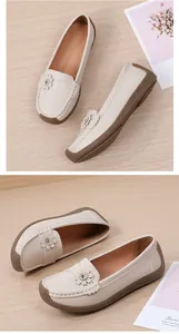 Detailopname van beige leren loafers met elegante bloemendecoratie op de neus.